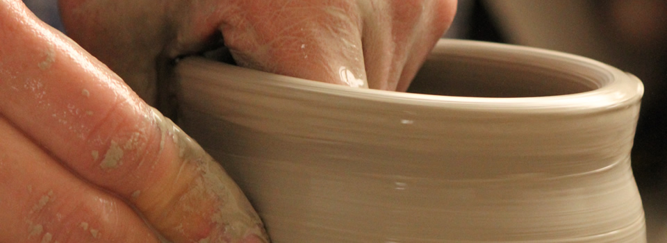 Hands shaping a pot on the potter's wheel